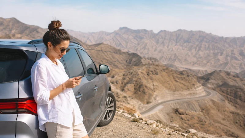 Traveller using a smartphone during road travellers beside car in Oman