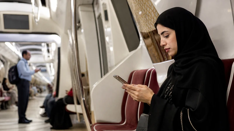 Traveller using a smartphone in commuter using a phone inside a modern Doha Metro carriage
