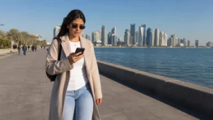 Traveller using a smartphone in winter visitor using a phone on the sunny Doha Corniche
