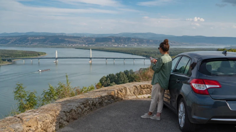 Road traveller checking mobile internet above a Danube bridge.