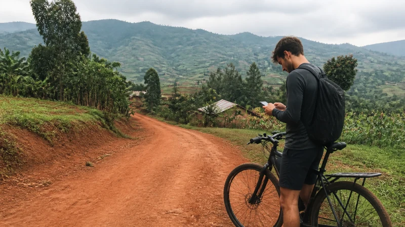 Cyclist checking mobile coverage on a rural road in Rwanda