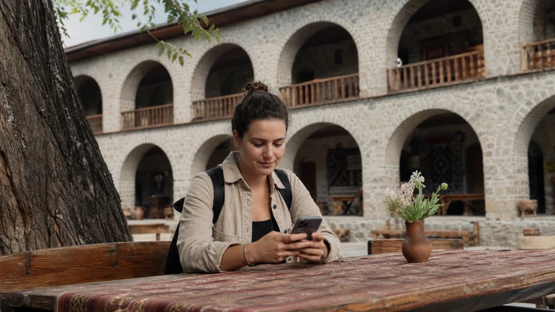 Traveller using an eSIM near historic Sheki architecture