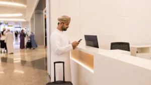 Traveller using a smartphone during traveller near neutral SIM counter at Muscat Airport