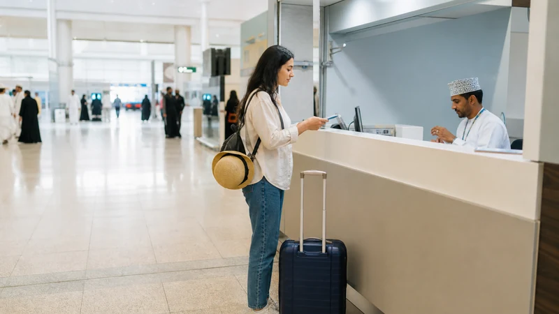 Traveller using a smartphone during traveller near neutral SIM counter at Salalah Airport