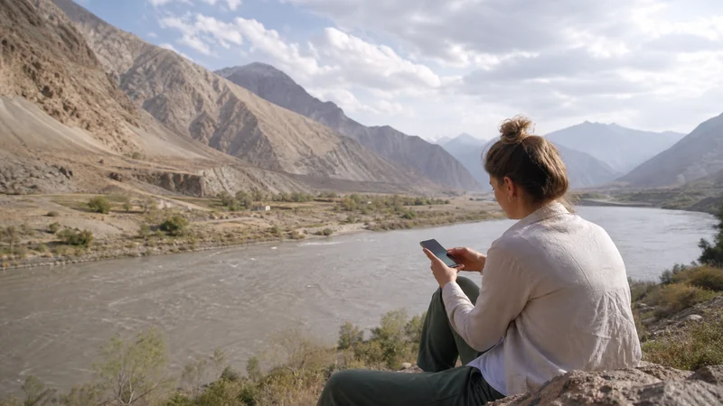 Traveller using a smartphone for tajikistan–afghanistan border mobile internet and esim guide