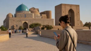 Tourist using a smartphone near Turkistan's historic mausoleum complex.