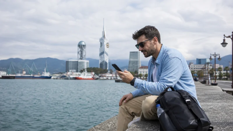 Traveller using a smartphone on the Batumi waterfront