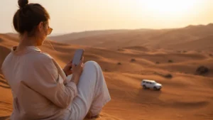 Traveller using a smartphone during visitor beside Wahiba Sands dunes